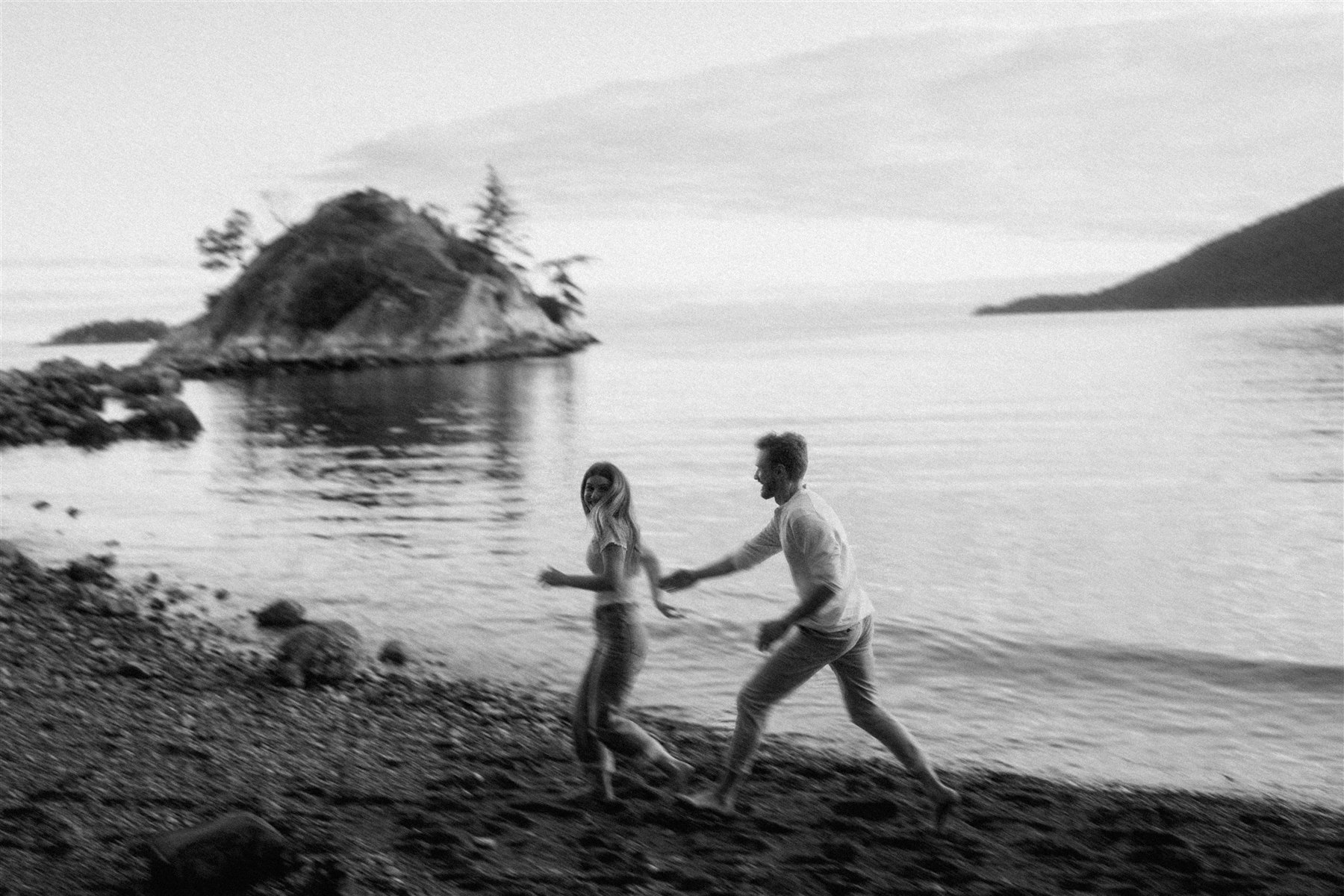 Nick chasing Carly along the shoreline during their engagement shoot