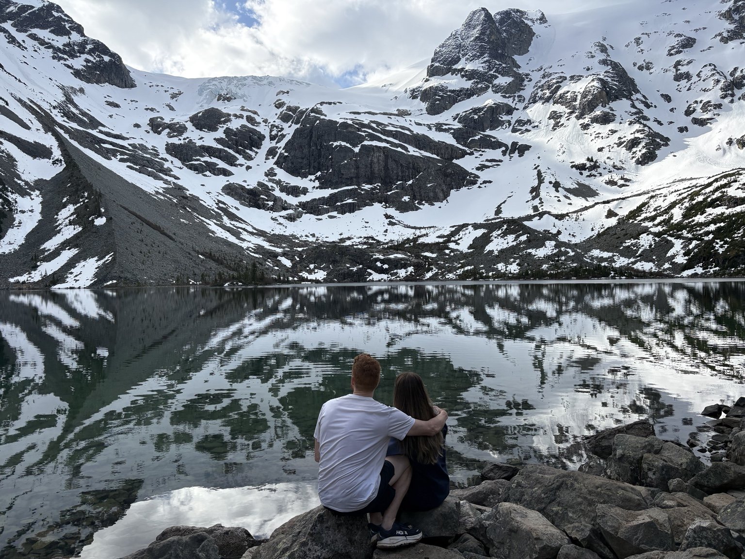 Nick and Carly sitting beside the turquoise water at Joffre Lakes